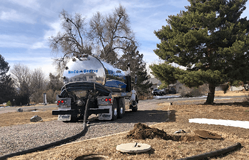 A vacuum truck is pumping water into a septic tank.