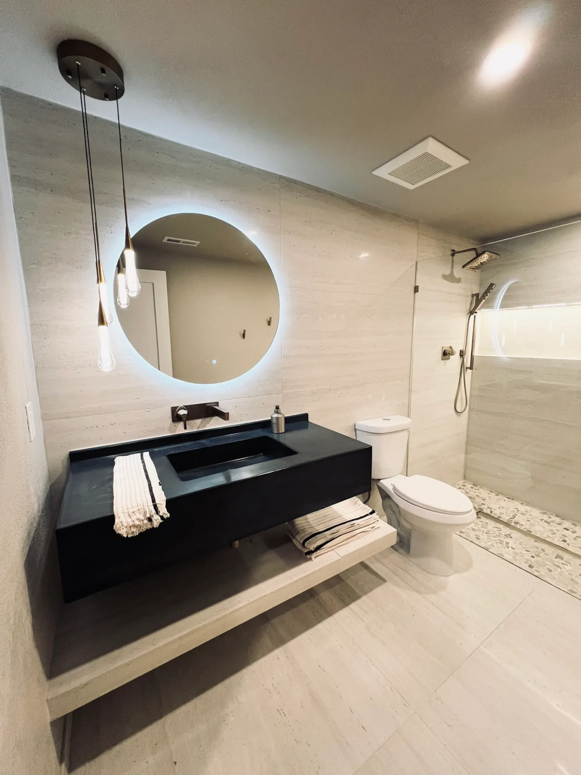 A bathroom with a toilet , sink , mirror and shower.