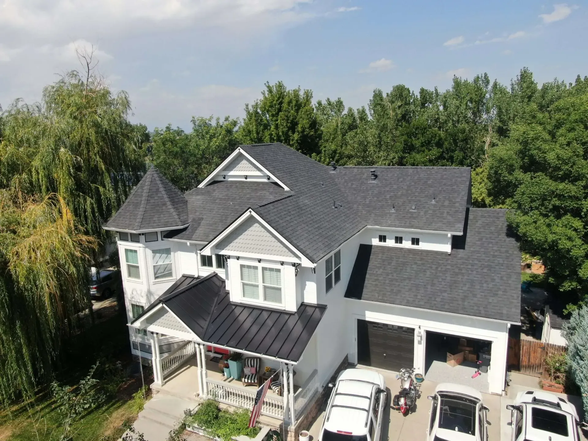 An aerial view of a large white house with a black roof.