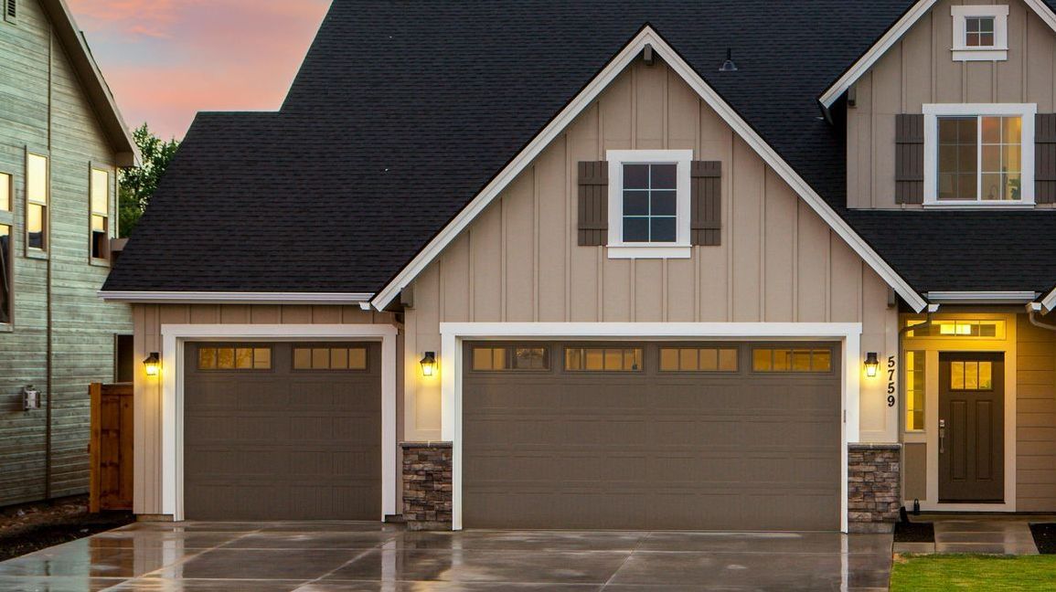 A house with two garage doors and a driveway in front of it.
