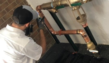A man is working on a pipe in a room.