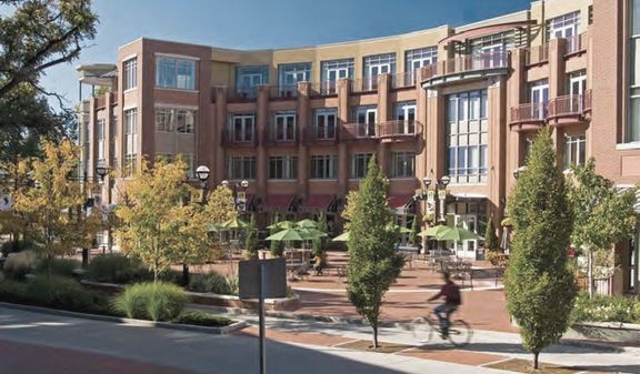 A man is riding a bike in front of a large building.