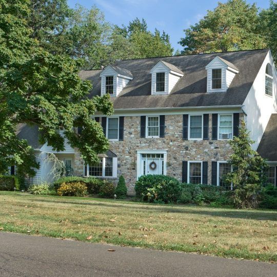 A large stone house with black shutters and a wreath on the door