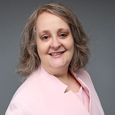 a woman in a purple shirt is smiling for the camera .