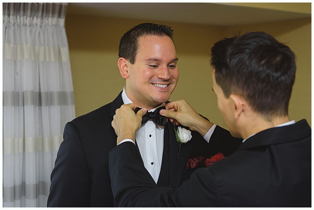 Bride laughs with three bridesmaids in red dresses, holding bouquets.
