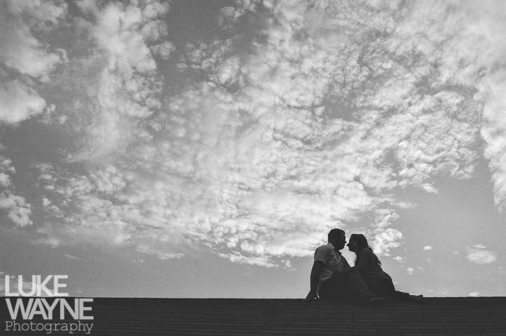 Couple silhouetted on steps against a dramatic, cloudy sky.