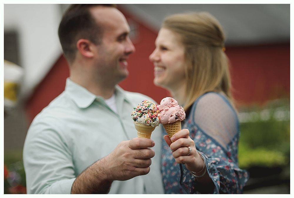 Groom smiles at camera, surrounded by groomsmen in navy suits and burgundy ties, outdoors.
