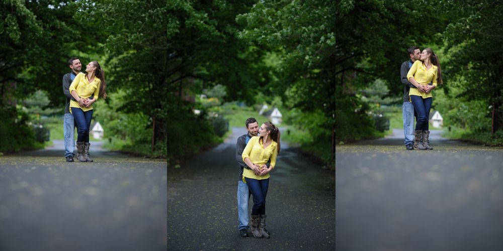 Bride and groom embrace outdoors, groom kisses bride's cheek. Black and white photo with blurred forest background.