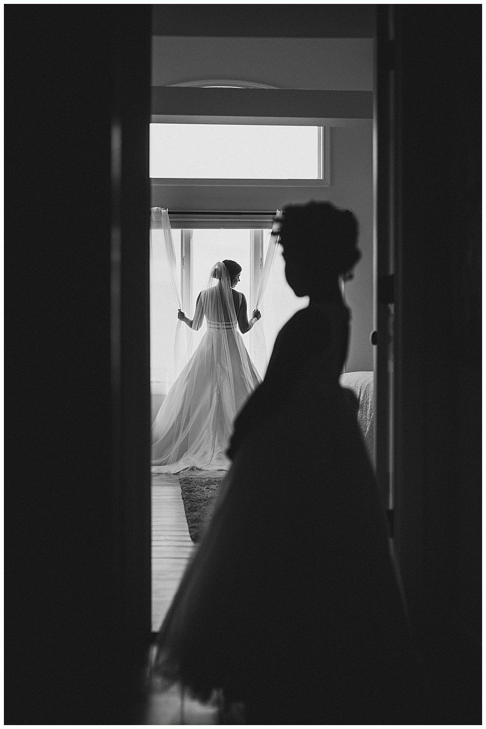 Bride in white dress holding bouquet, standing under weeping willow.