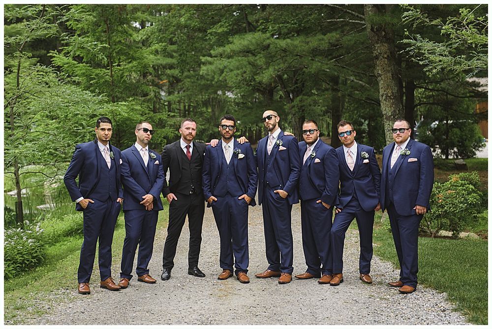 Men in a wooden building, some holding drinks, one toasting. Black and white.