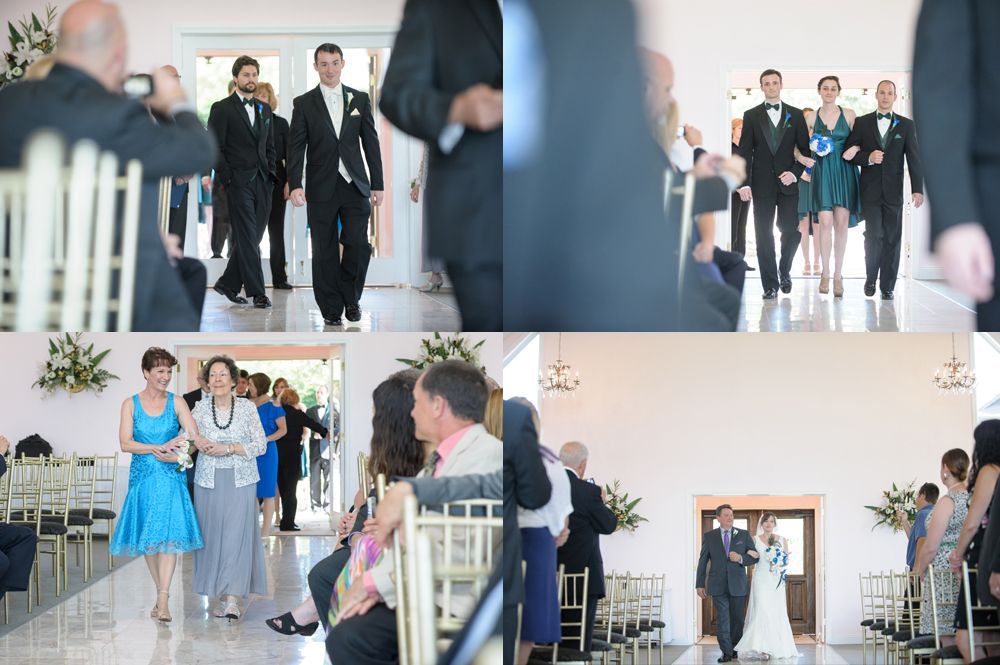 Two men in suits stand on a road. One has arms crossed, a yellow tie. The other is beside him, also in a suit, with dark sunglasses.