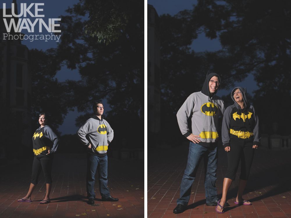 Couple wearing Batman hoodies poses outdoors at night.