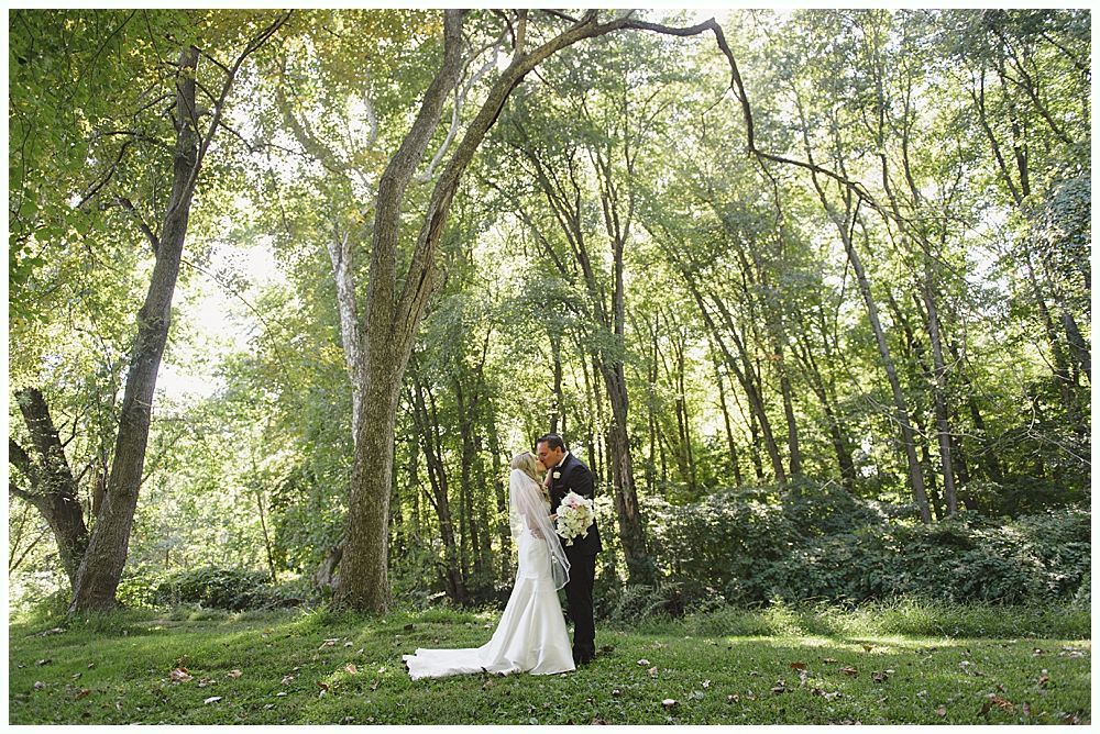 Men in a wooden building, some holding drinks, one toasting. Black and white.