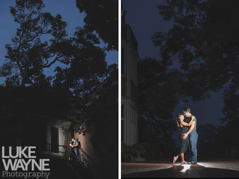 Couple kissing under a tree at dusk, near a building.