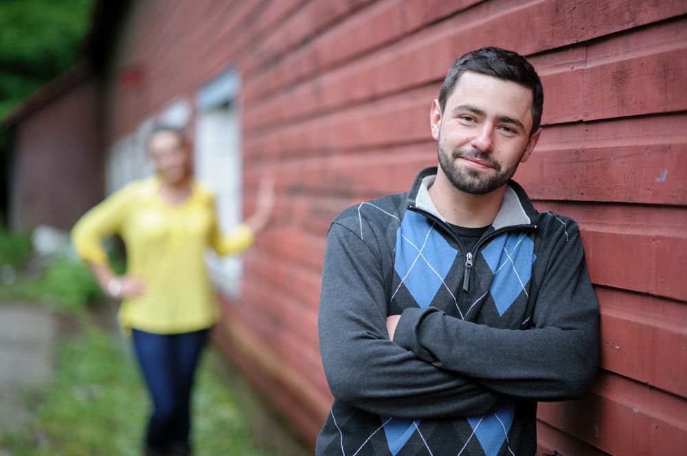 Bride walks down a path with two men, holding a yellow bouquet. Fountain and building in the background.