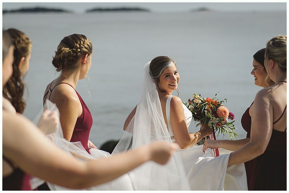 Wooden wedding arch decorated with greenery and red and white flowers, outdoors.