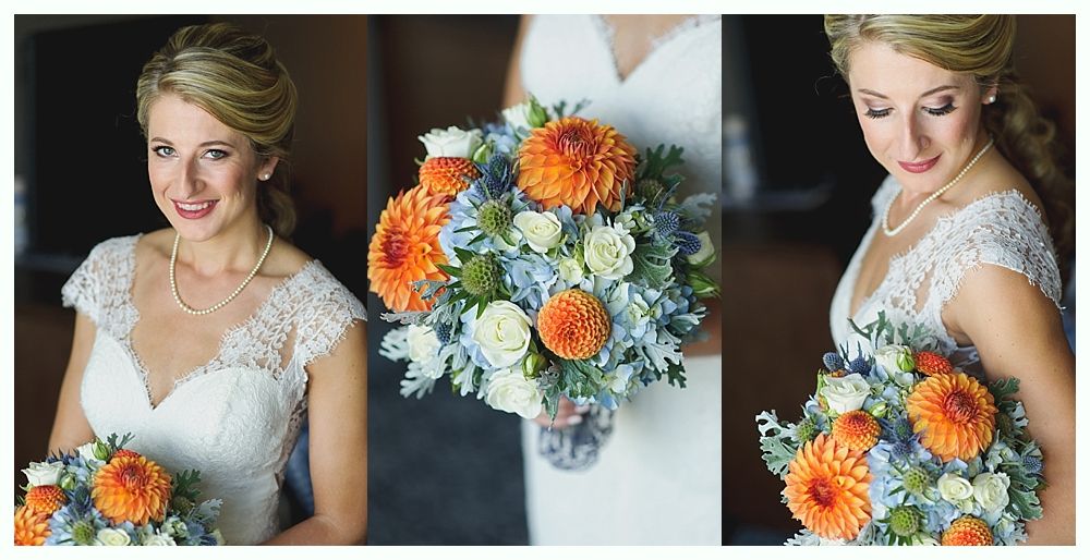 Bride in a white lace dress smiles, holding an orange and blue floral bouquet.