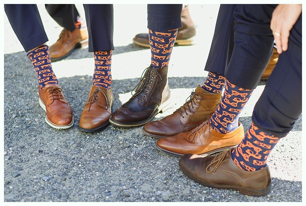 Feet wearing patterned socks and dress shoes on pavement.