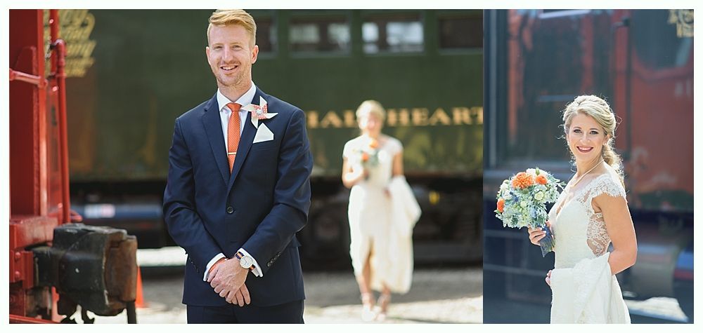 A groom smiles in front of a train as two brides walk toward him with bouquets, outdoors.