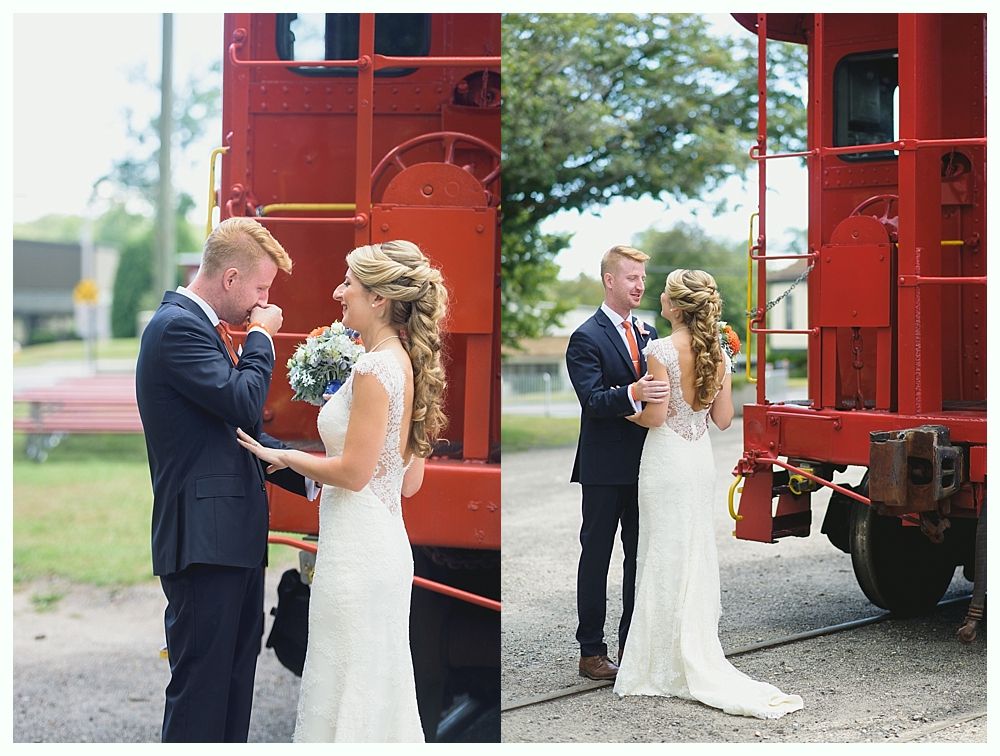 Wedding couple by a red train caboose. Groom cries, bride smiles.