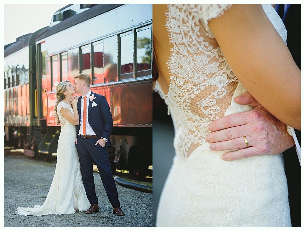 Bride and groom kissing by a train; detail of the bride's lace back with a hand on her waist.