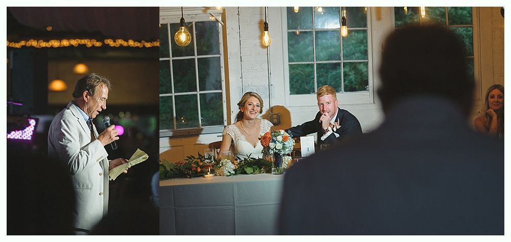 Wedding reception: speaker giving toast, bride and groom seated, audience listening.