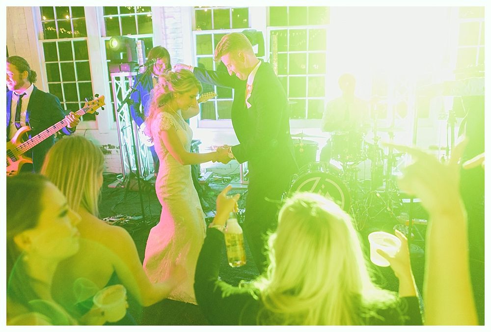 People dancing at an event, a band playing music. Bright yellow and green lighting.