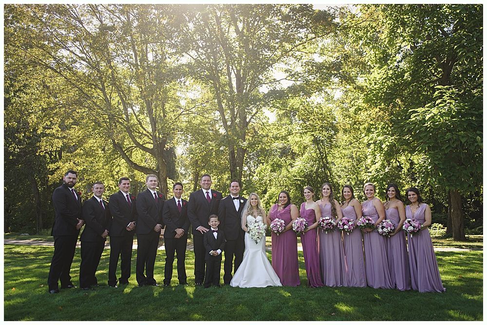 Wedding ceremony: Bride and groom walking toward barn, bridesmaids in red dresses holding bouquets.