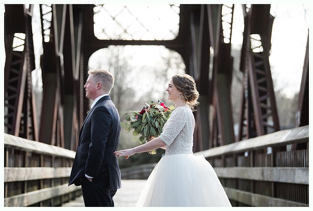 Wedding ceremony with groom and groomsmen smiling, floral arch in background.