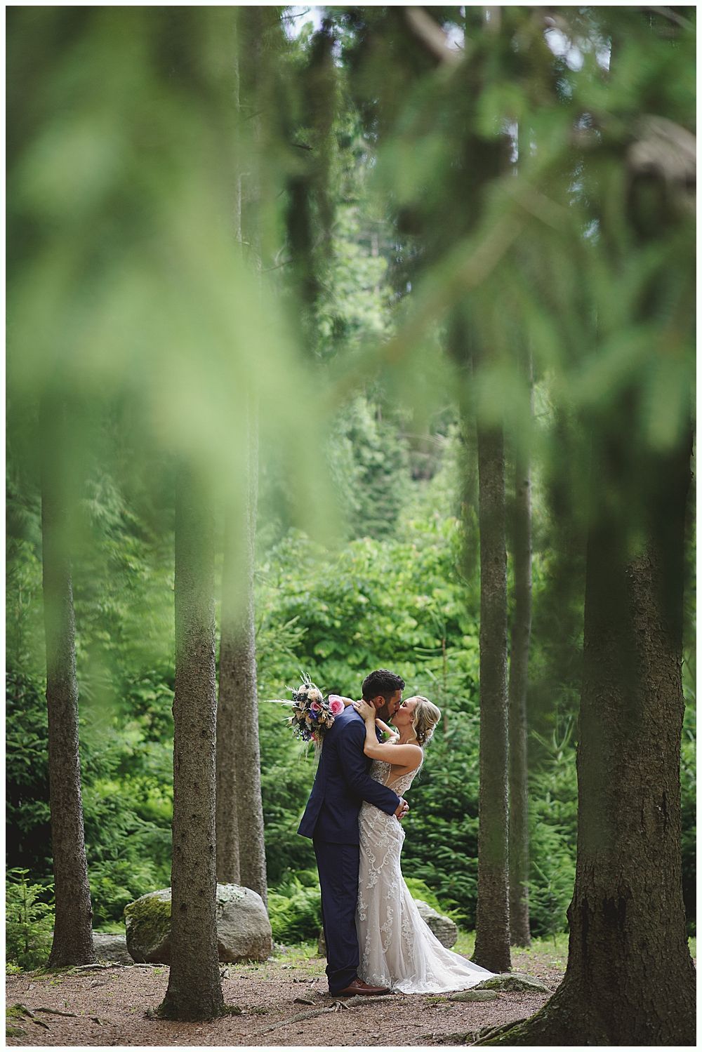 Bride hugging a man near outdoor wedding seating. People watch. The bride wears a white dress and veil.