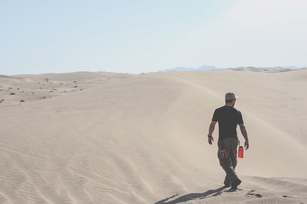 Couple kissing near trees at night with glowing streetlights in foreground.