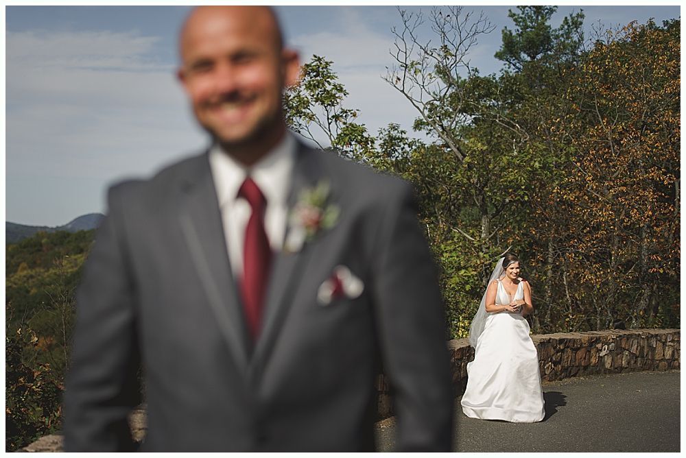 Bride hugging a man near outdoor wedding seating. People watch. The bride wears a white dress and veil.