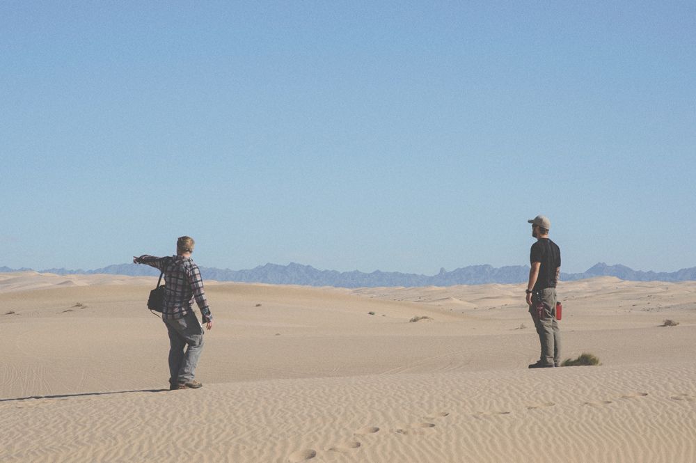 Bride and groom embrace, lit by spotlight against dark night sky and hillside.