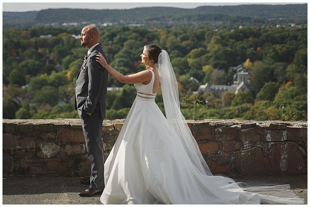 Couple embracing, noses touching, looking at each other. Snowy outdoor setting. Woman's hand with engagement ring visible.