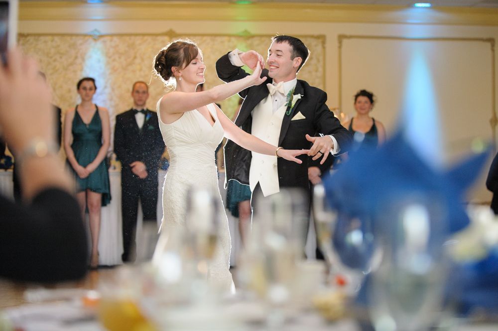 Couple kissing near trees at night with glowing streetlights in foreground.