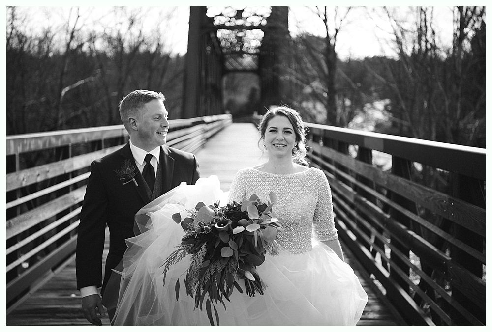 Wedding ceremony. Guests seated, smiling. Groom facing officiant. Bride in white dress. Outdoors, sunny day.
