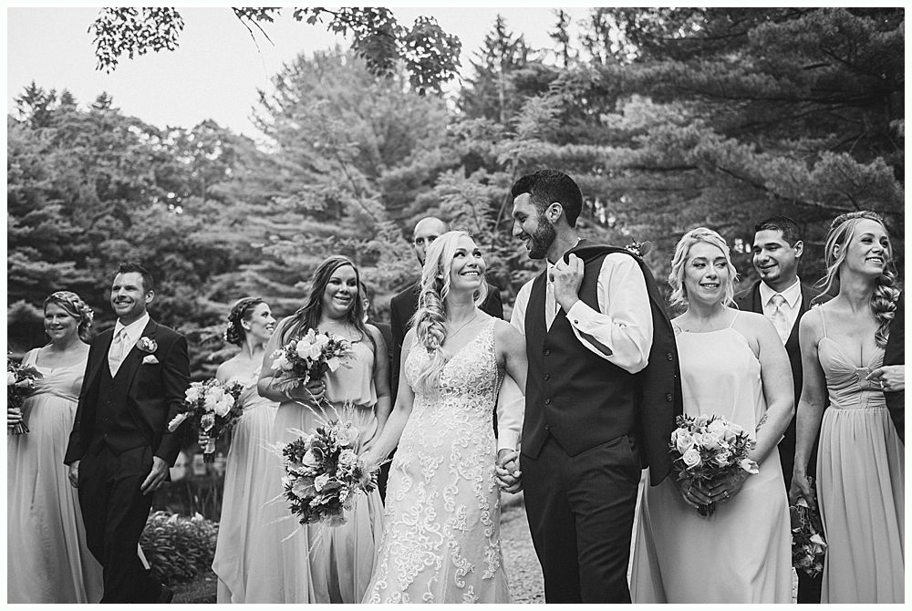 Woman in a crowd, smiling and resting her chin on her hand, at an outdoor event.