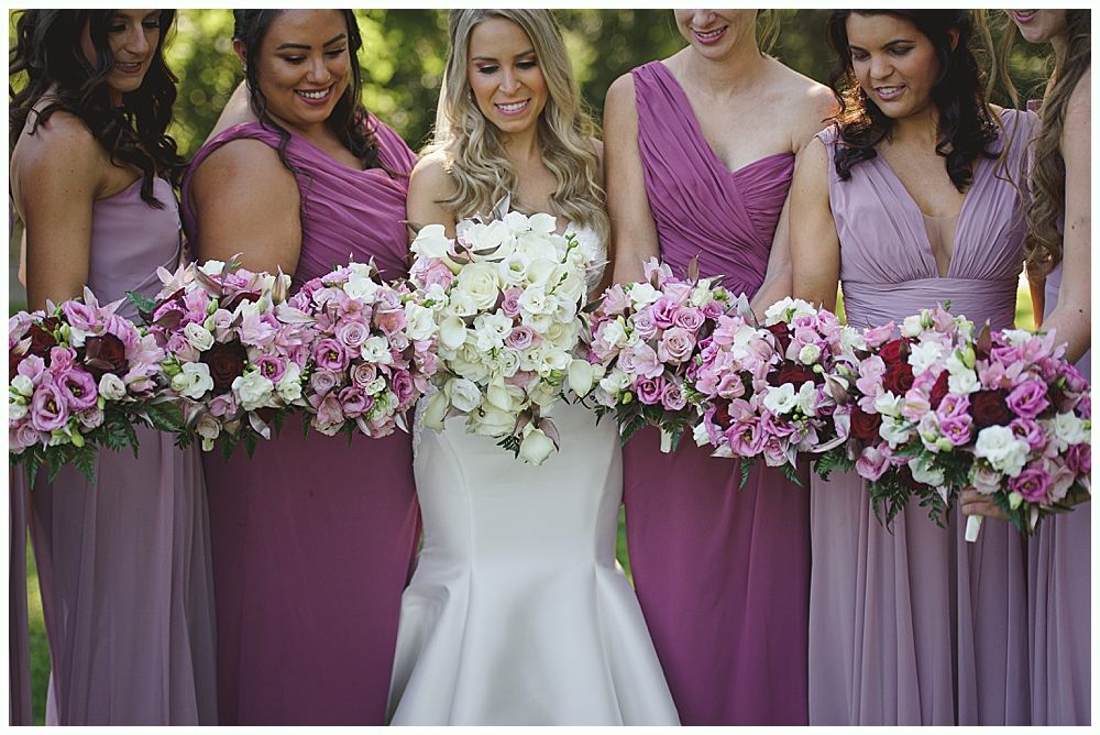 Woman in a crowd, smiling and resting her chin on her hand, at an outdoor event.