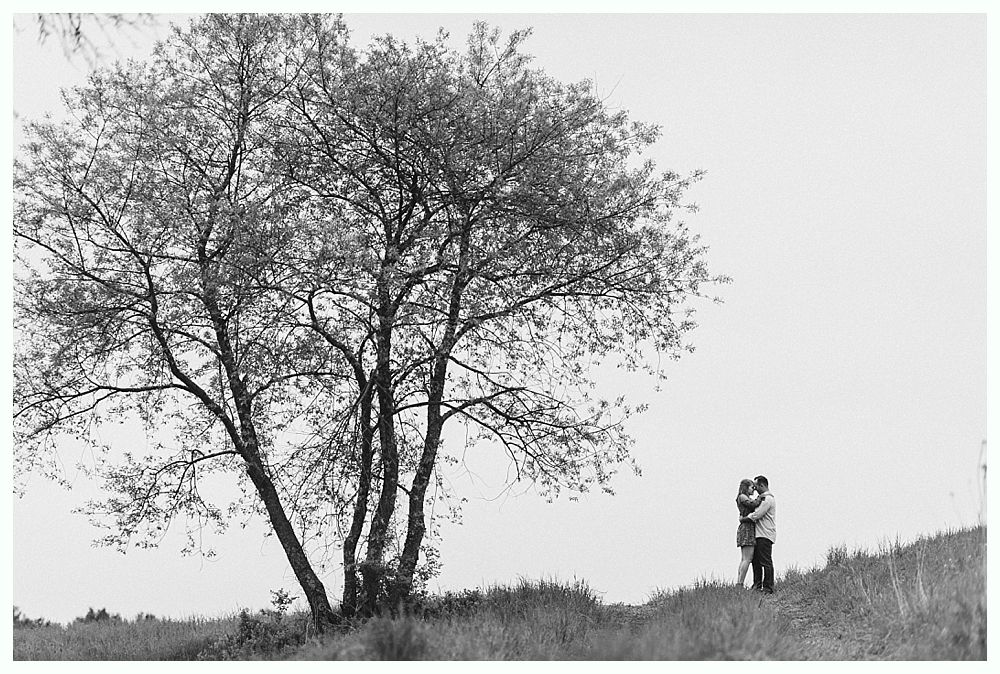 Woman holding a glass, smiling. Another woman is visible in the background, also smiling. Black and white.