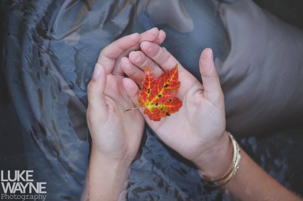 Couple smiling, embracing. Woman in denim jacket, man in light green shirt, outdoors.