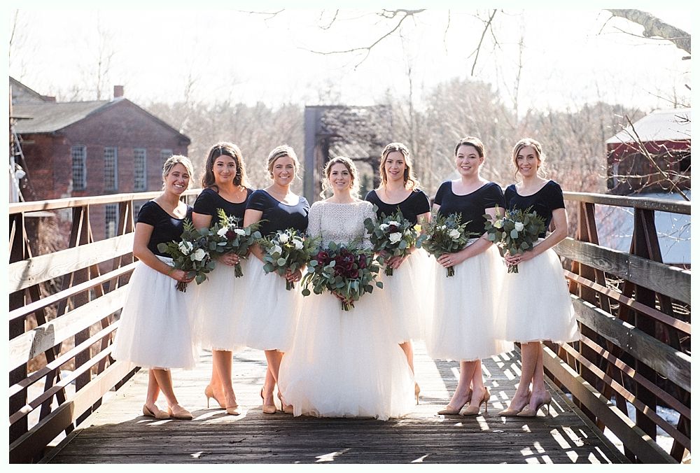 Wedding ceremony: Couple kissing at altar under weeping willow tree; bridal party and guests watching.