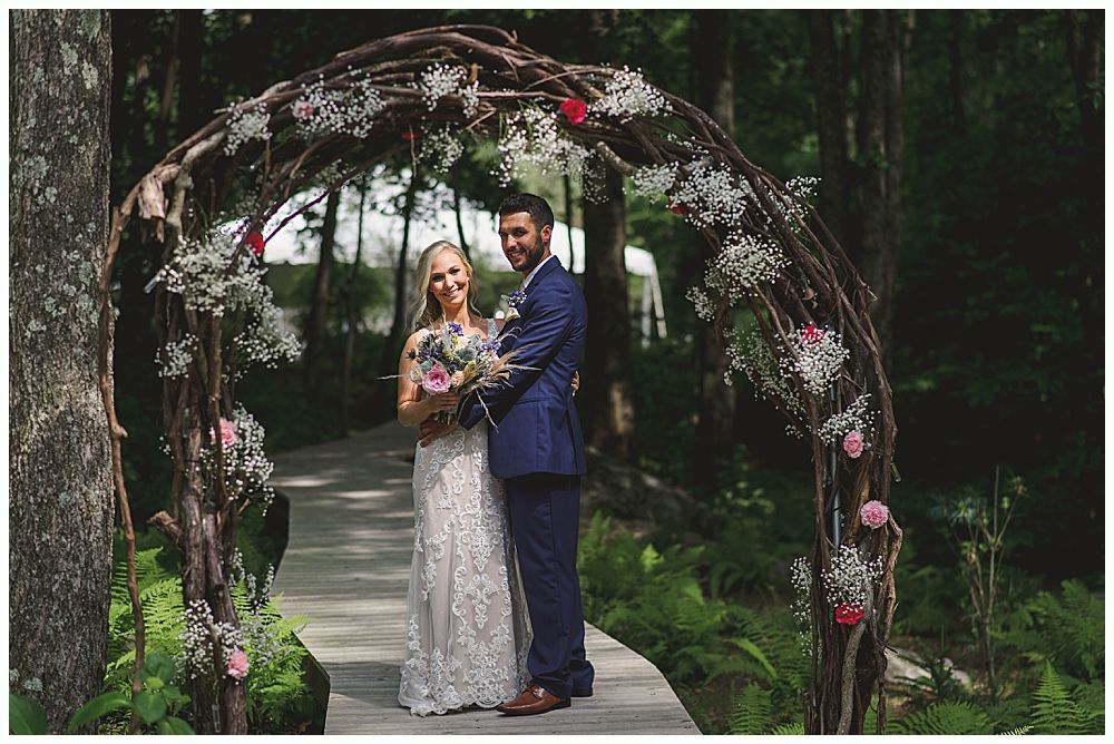 Wedding ceremony: Couple kissing at altar under weeping willow tree; bridal party and guests watching.