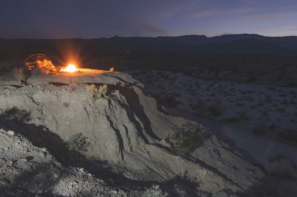Person taking photo in mirror, indoors; black and white.