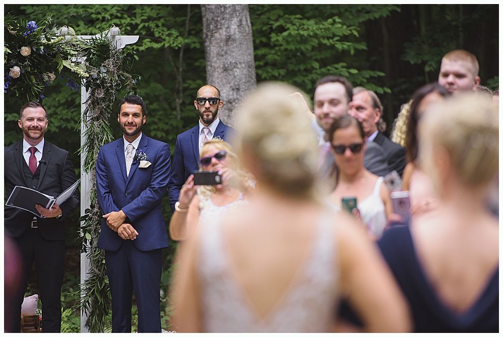 Newlyweds celebrating with champagne outside a building. Bride holding bouquet and bottle. Another person laughs in the background.