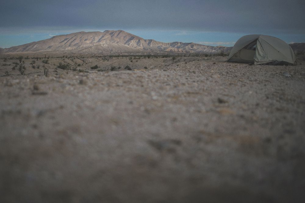 Person taking photo in mirror, indoors; black and white.