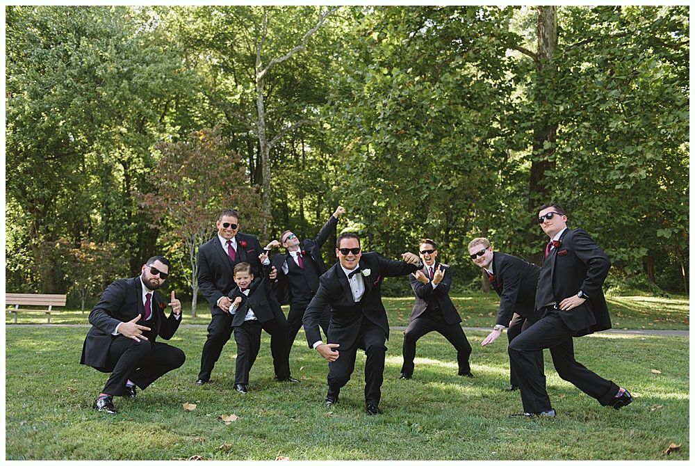 Newlyweds celebrating with champagne outside a building. Bride holding bouquet and bottle. Another person laughs in the background.