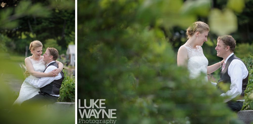 A newly married couple laughing in a garden. The bride touches the groom's shoulder.