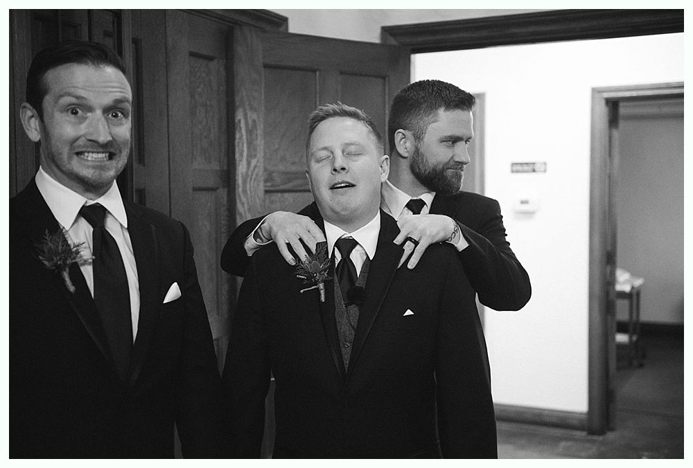Wedding party walking on a grassy lawn; bride and groom in center, bridesmaids in red, groomsmen in navy.