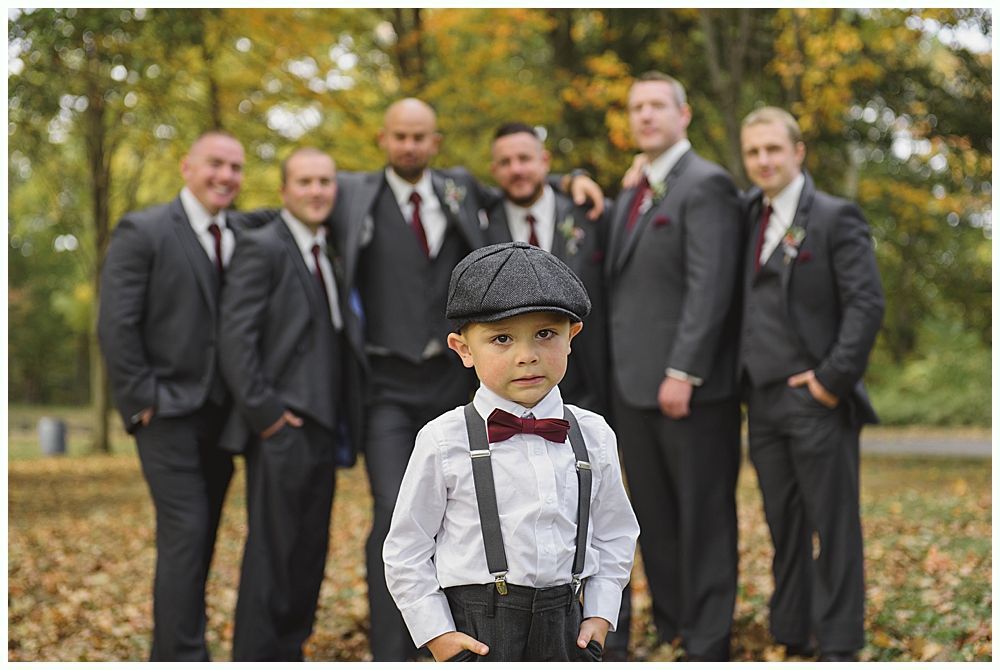 Bride in a white wedding dress smiles, looking over her shoulder as her veil blows in the wind outdoors.