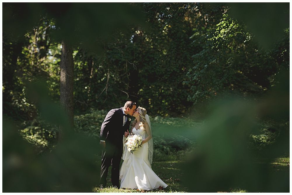 Wedding party walking on a grassy lawn; bride and groom in center, bridesmaids in red, groomsmen in navy.